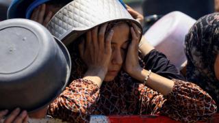 A Palestinian girl reacts while waiting to receive food from a soup kitchen, amid a hunger crisis, in Gaza City, July 22, 2025
