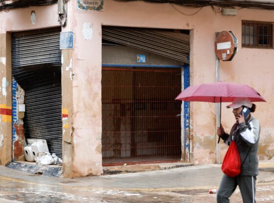 A pedestrian with an umbrella walks past a building damaged by flash floods in Catarroja municipality, Valencia, Spain.