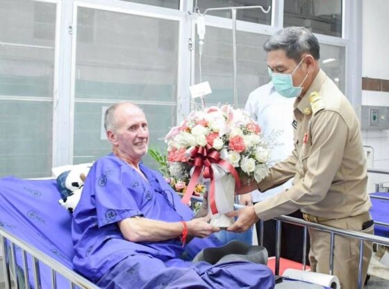 Vernon Unsworth, the British rescuer, receiving a bouquet of flowers in the hospital from a Thai official.