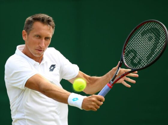 Former tennis player Sergiy Stakhovsky hitting a forehand with a tennis ball in motion.