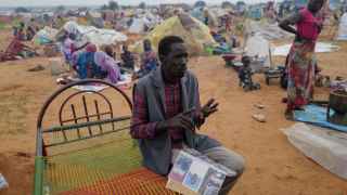 A man holds an album with photos of his son and his father, killed by the FAR west of Darfur.