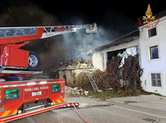 Firefighters working at night to extinguish a fire in a building with a collapsed roof.