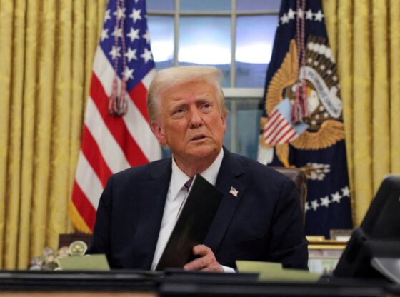 U.S. President Donald Trump in the Oval Office at the White House on Inauguration Day, holding documents as he issues executive orders and pardons.